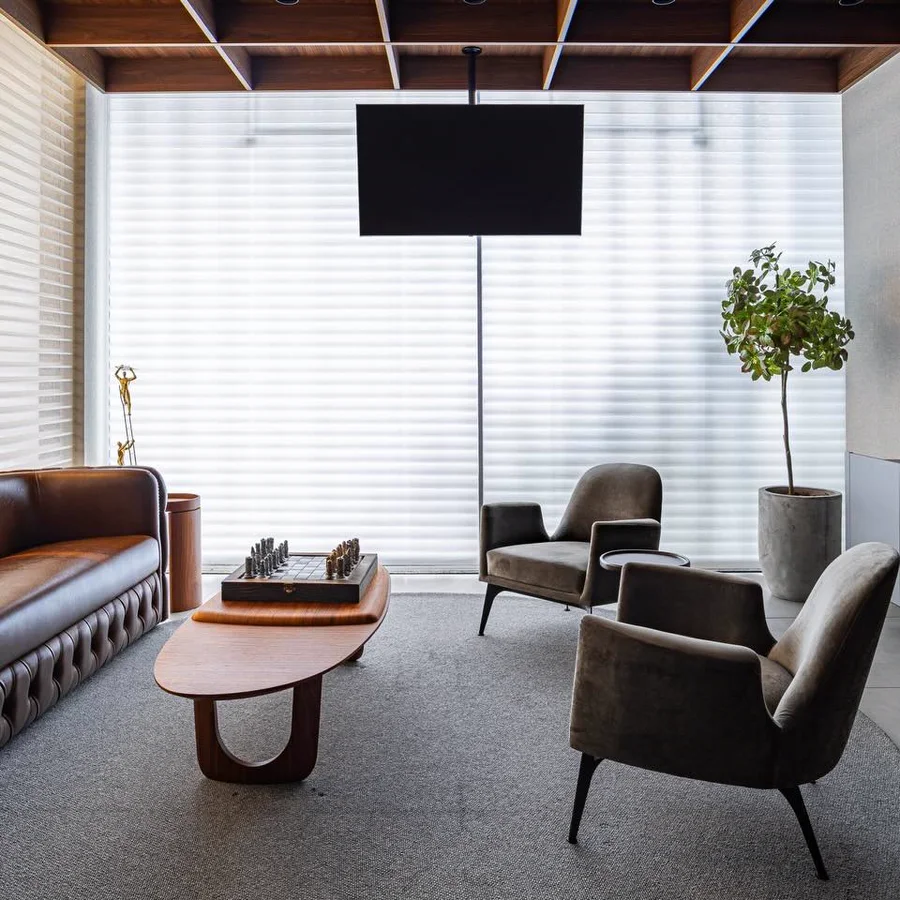 Lounge corporativo com TV suspensa, persianas motorizadas e estar integrado