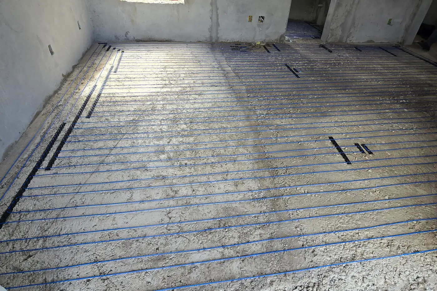 Instalação de piso aquecido em obra — serpentina assentada sobre o contrapiso