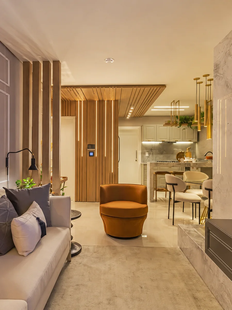 Living residencial com iluminação cênica embutida em painel ripado, keypad de cenas na parede e cozinha integrada ao fundo